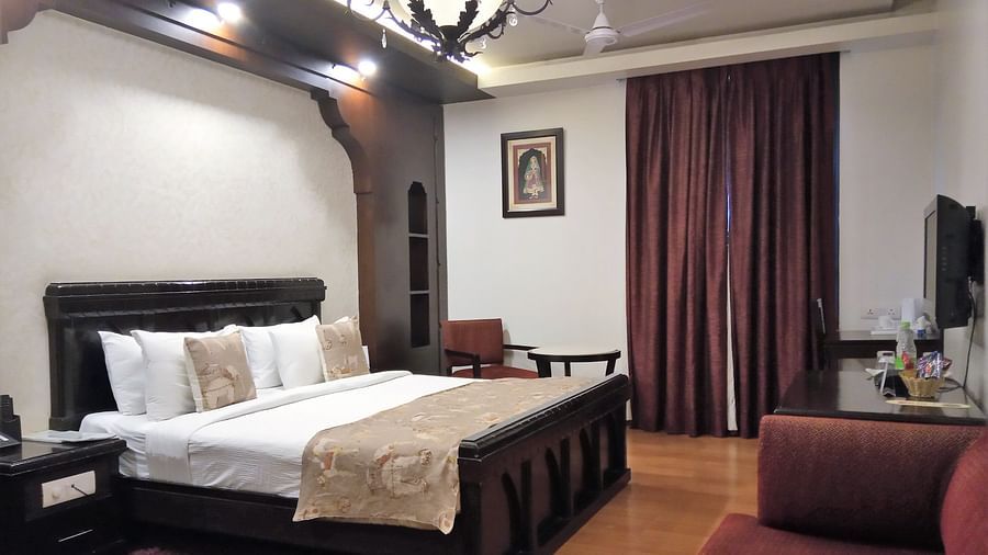 Elegant hotel room at Rockland Hotel, CR Park, featuring classic wooden furniture, chandelier lighting, and warm tones for a luxurious stay.