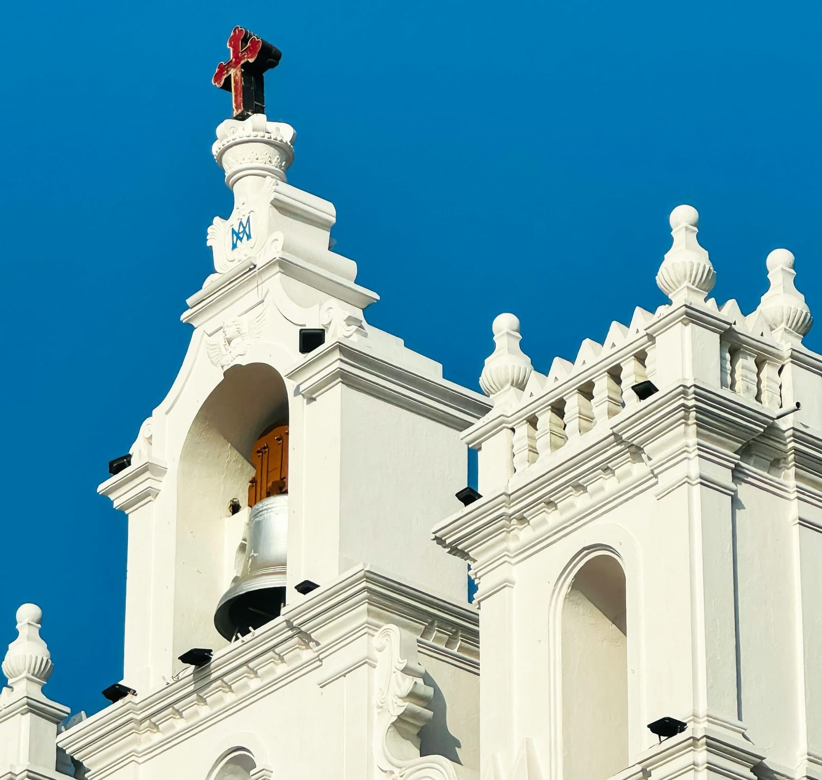 A close-up shot of a white-coloured church building with a plain blue sky in the background.