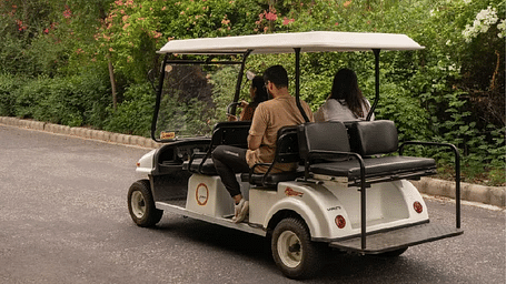 Rear view of a golf cart carrying two people on a road at Karma Chalets.