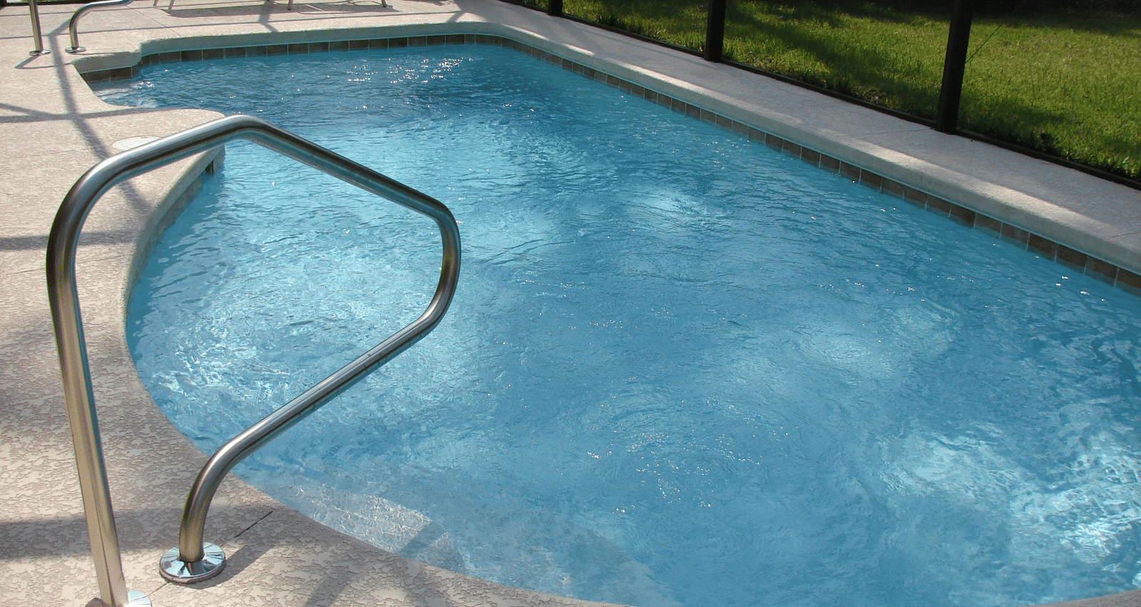 An outdoor swimming pool surrounded by a metal fence.