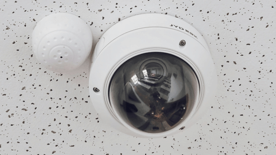 Dome security camera installed on a speckled white ceiling.
