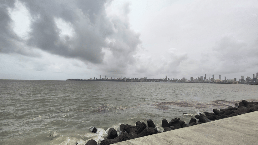 Dark monsoon clouds gather over Marine Drive, with waves rolling across the Arabian Sea.