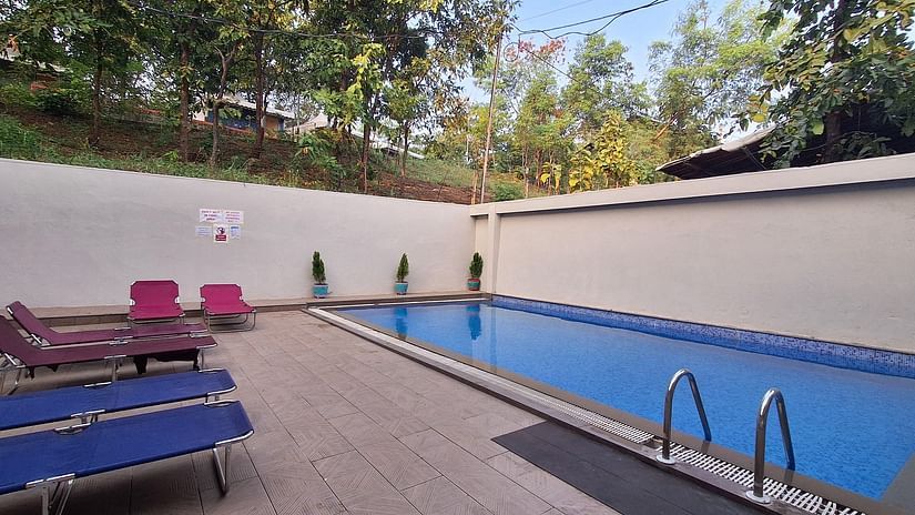 an image of a swimming pool with sun decks surrounded by the trees at VITS Roccia Hill Resort & Adventure Park.