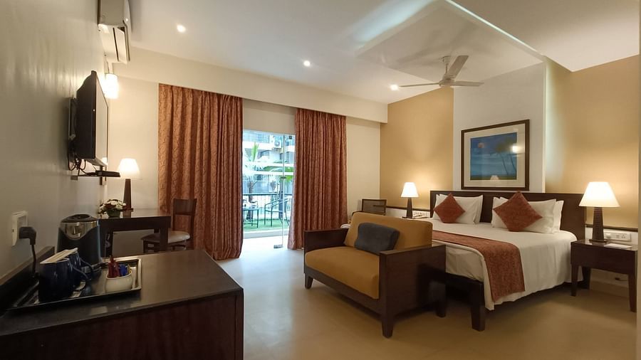 Image of Studio Room with Garden, showcasing a wall-mounted TV unit and a door leading to the balcony at Kyriad Prestige Calangute, Goa