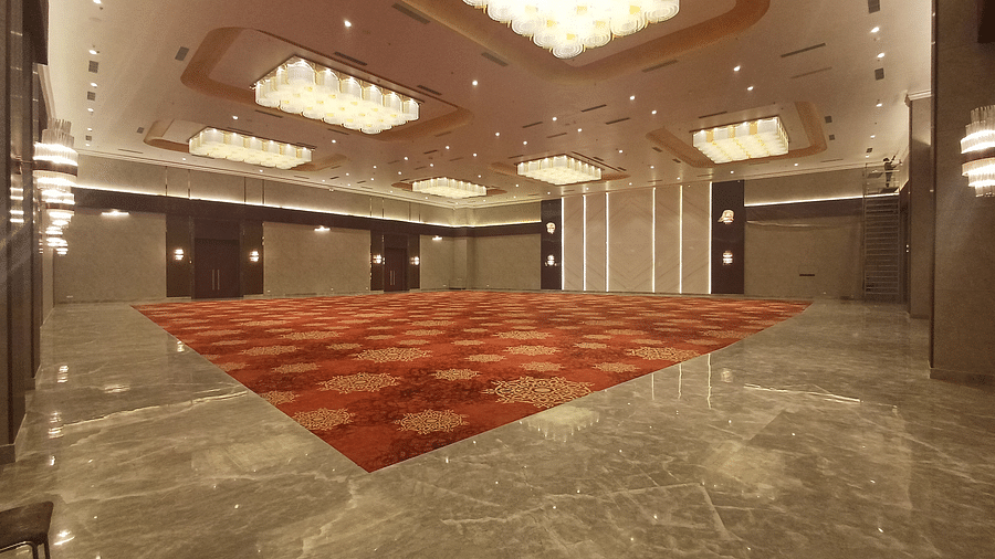A wide interior shot of a hall at The Gaurs Sarovar Premiere with a patterned carpet and decorative ceiling lights.