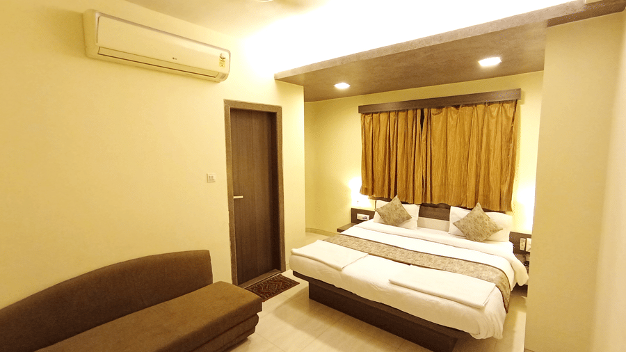 executive room featuring a brown sofa, double bed, window with brown drapes, and a split air conditioner.