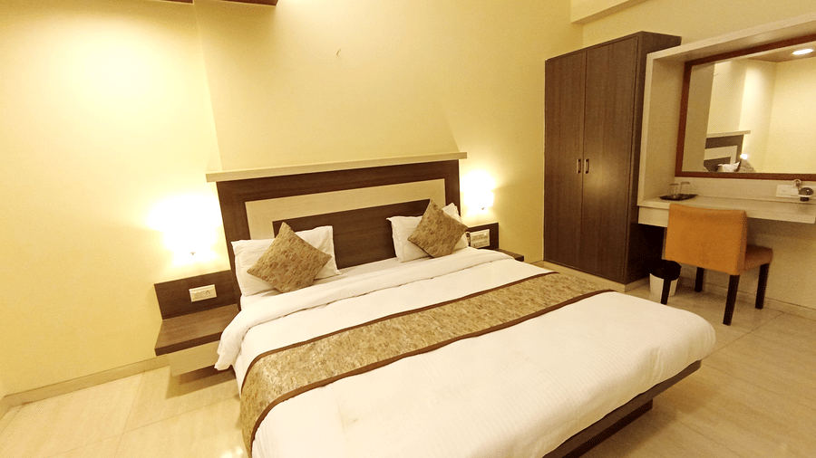 executive room featuring a double bed, wooden furniture set, vanity mirror, and warm ambient lighting.