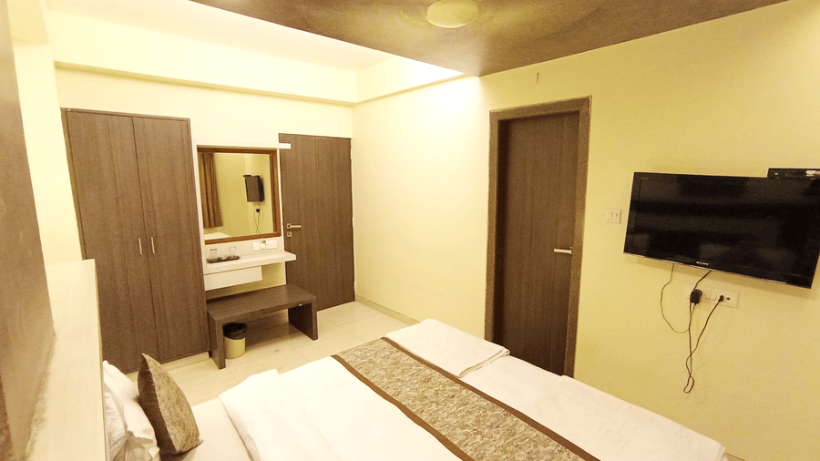 Angled view of executive room featuring a double bed, wall-mounted television, wardrobe, and vanity dresser.