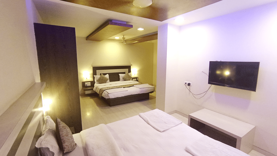 A family room featuring a wall-mounted flat-screen TV and two double beds visible in a spacious layout.