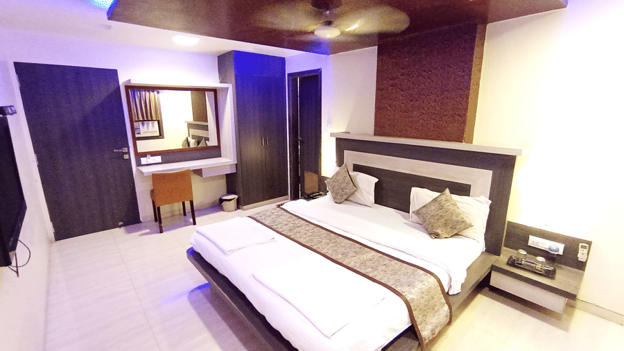suite room interior with blue LED accent lighting, a large bed, vanity mirror, and dark wood finishes.