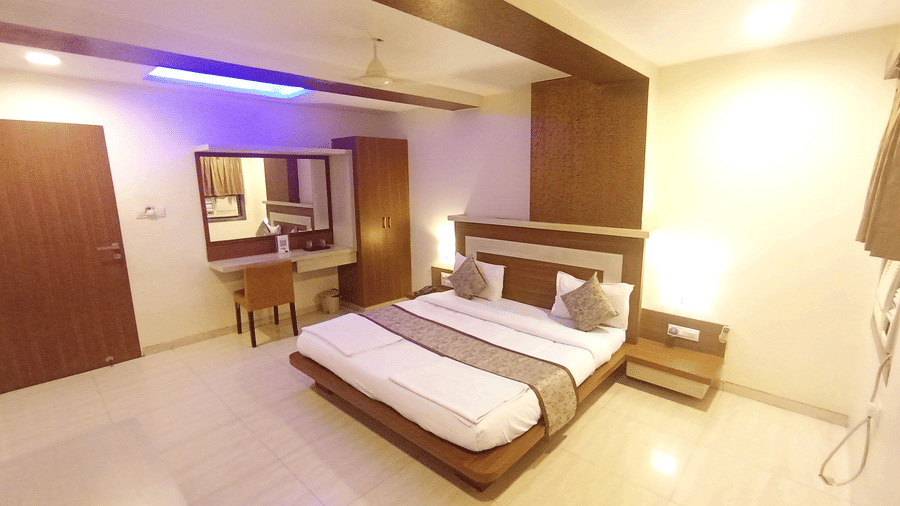 Wide view of the suite room with a double bed, dressing mirror desk, and accent strip lighting on the ceiling.