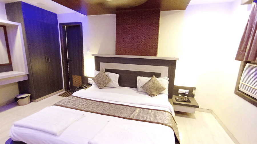 Wide view of suite room featuring a large double bed, vanity table, and subtle purple mood lighting on the ceiling.
