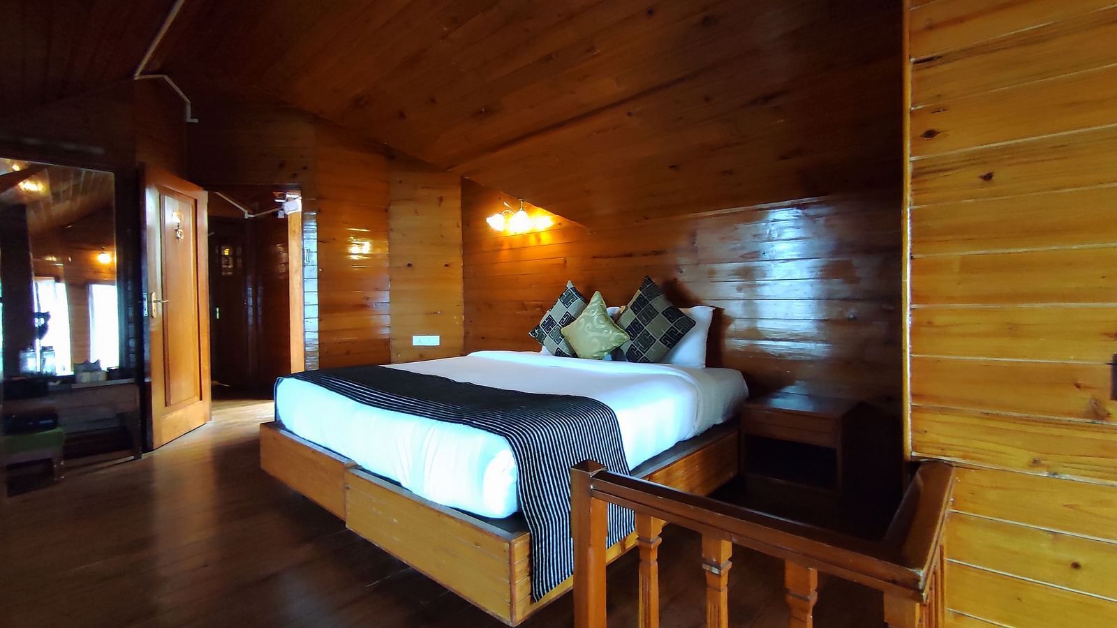 A double bed placed centre stage at Cedar Inn in Darjeeling with a door opening to the hallway.