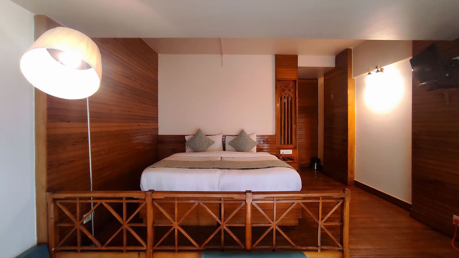 The Deluxe Room in Cedar Inn, Darjeeling features a separate living area, and a double bed.