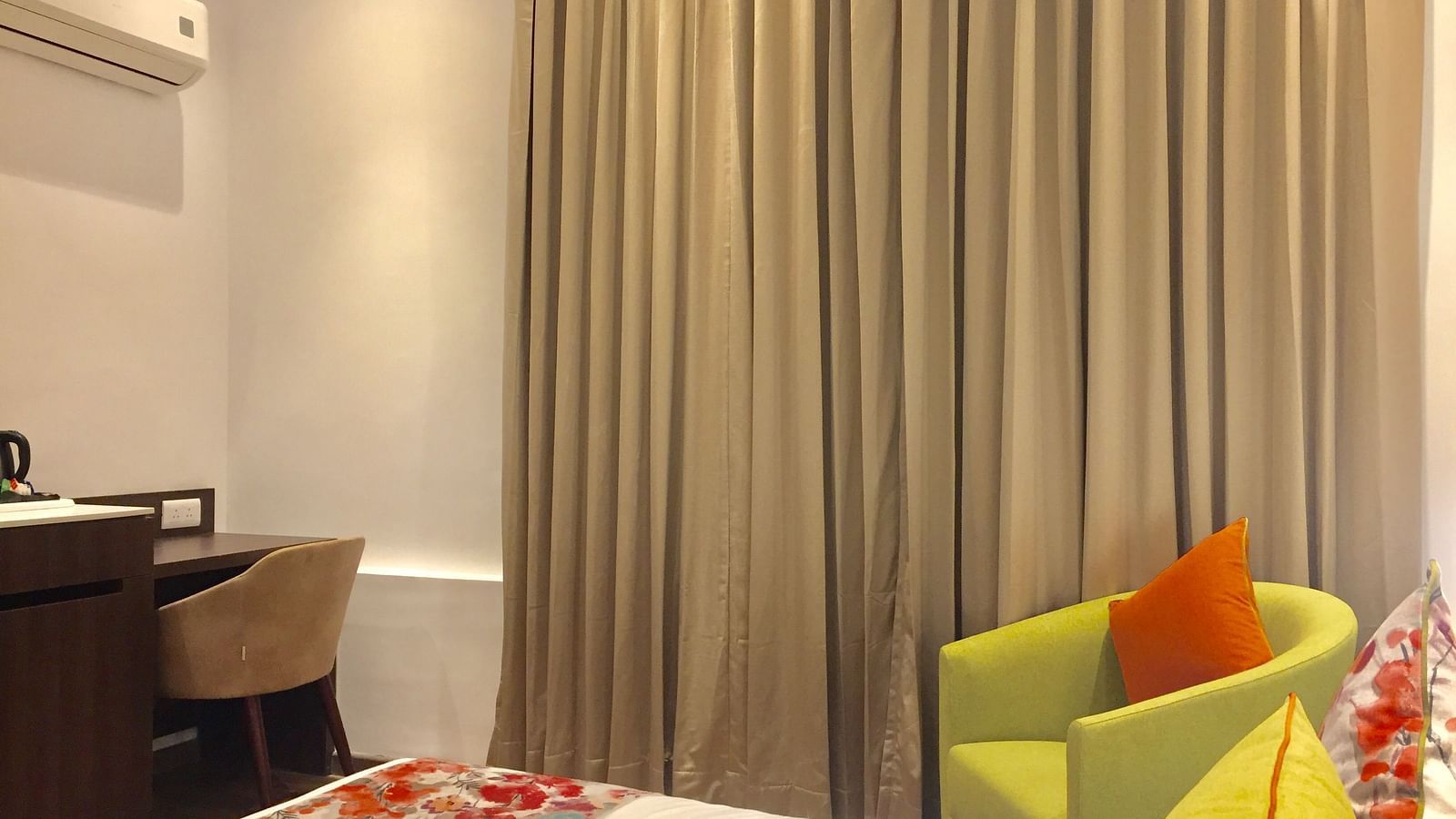 Deluxe Rooms at Hotel Le ROI Lake View Koti captured with curtained windows and green furniture inside the room2