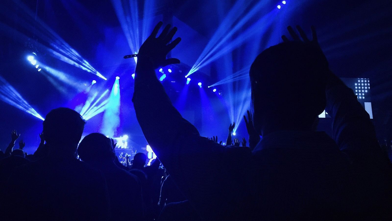 an image of a crowd enjoying DJ night illuminating blue light.