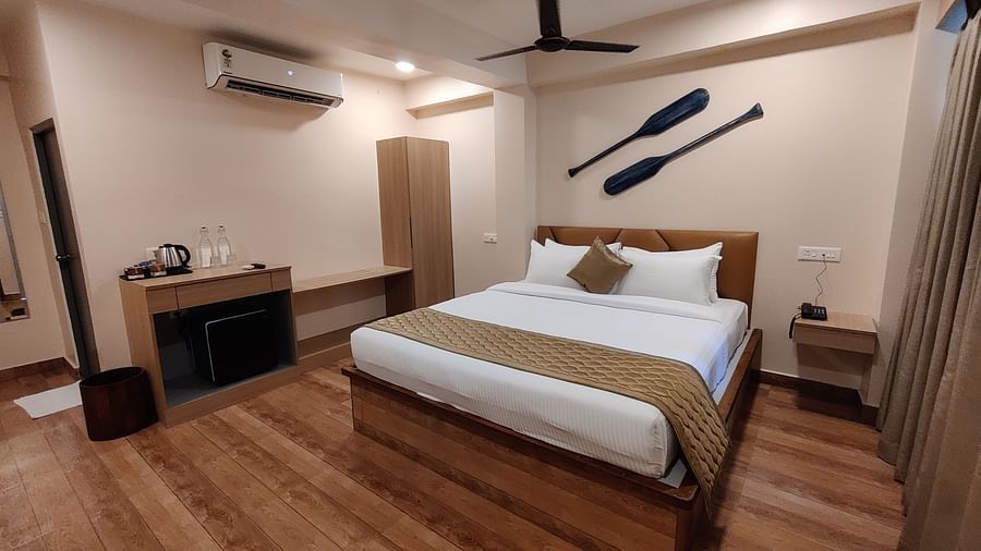 Spacious bedroom with a king-sized bed, wooden ceiling, and large windows overlooking greenery