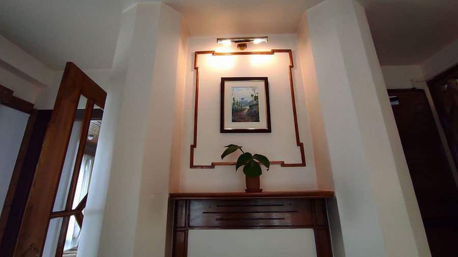 The mantel of Executive Suite with a framed picture that is highlighted by a light at Cedar Inn in Darjeeling.