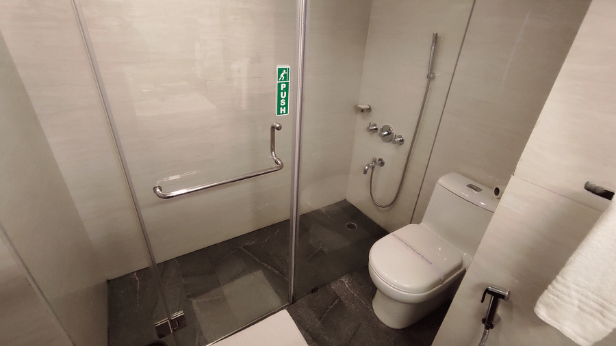 Bathroom area of the Executive Suite at Cedar Inn with a glass enclosed shower section, toilet, towel setup, and tiled flooring.