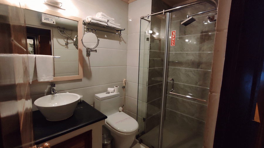 Modern bathroom featuring a floating vanity with round vessel sink, wall-mounted toilet, and frameless glass shower enclosure with tiled walls at Cedar Inn.