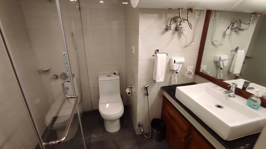 Contemporary bathroom with glass shower partition, wall-mounted toilet, and wooden vanity with vessel sink, tiled walls at Cedar Inn.