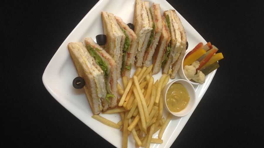 Club sandwiches served with golden french fries and black olives on a white plate | Daksh The Madhuvan Suites