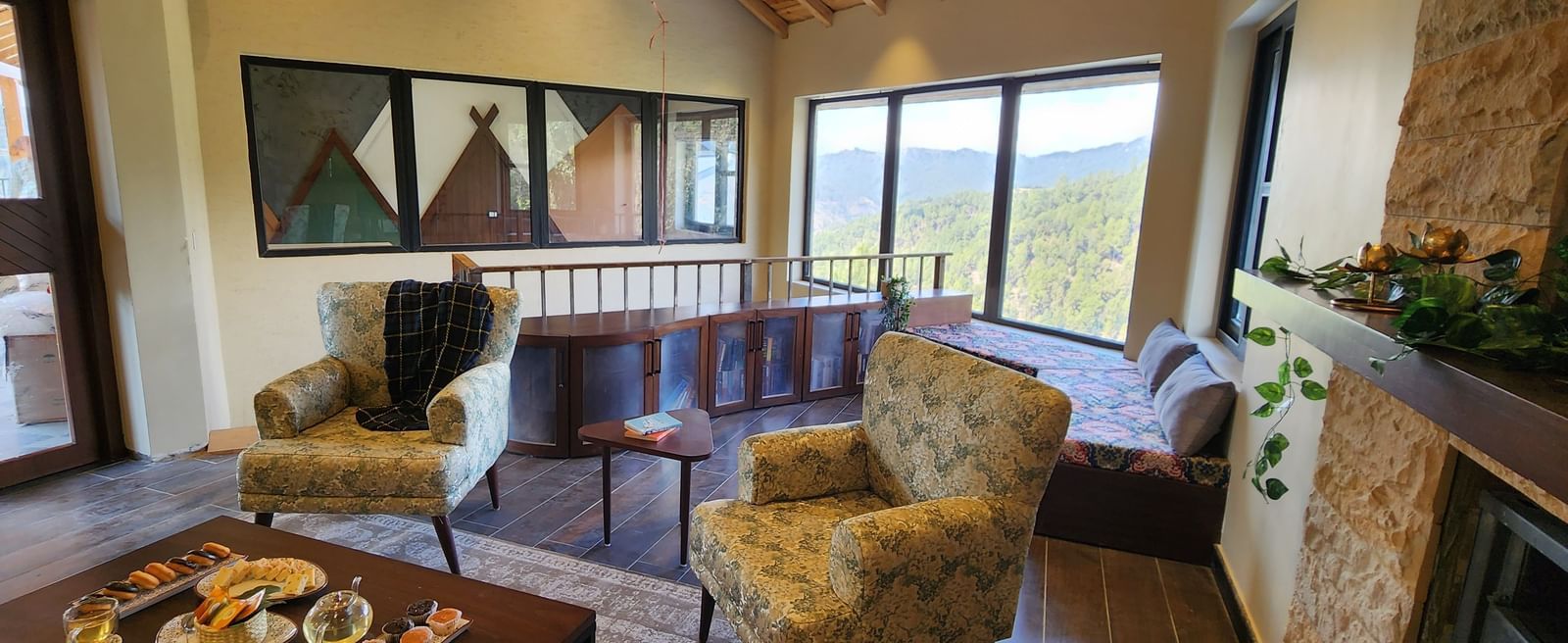 Cosy lounge with armchairs, coffee table, and panoramic window views at The Chamomile Estate.