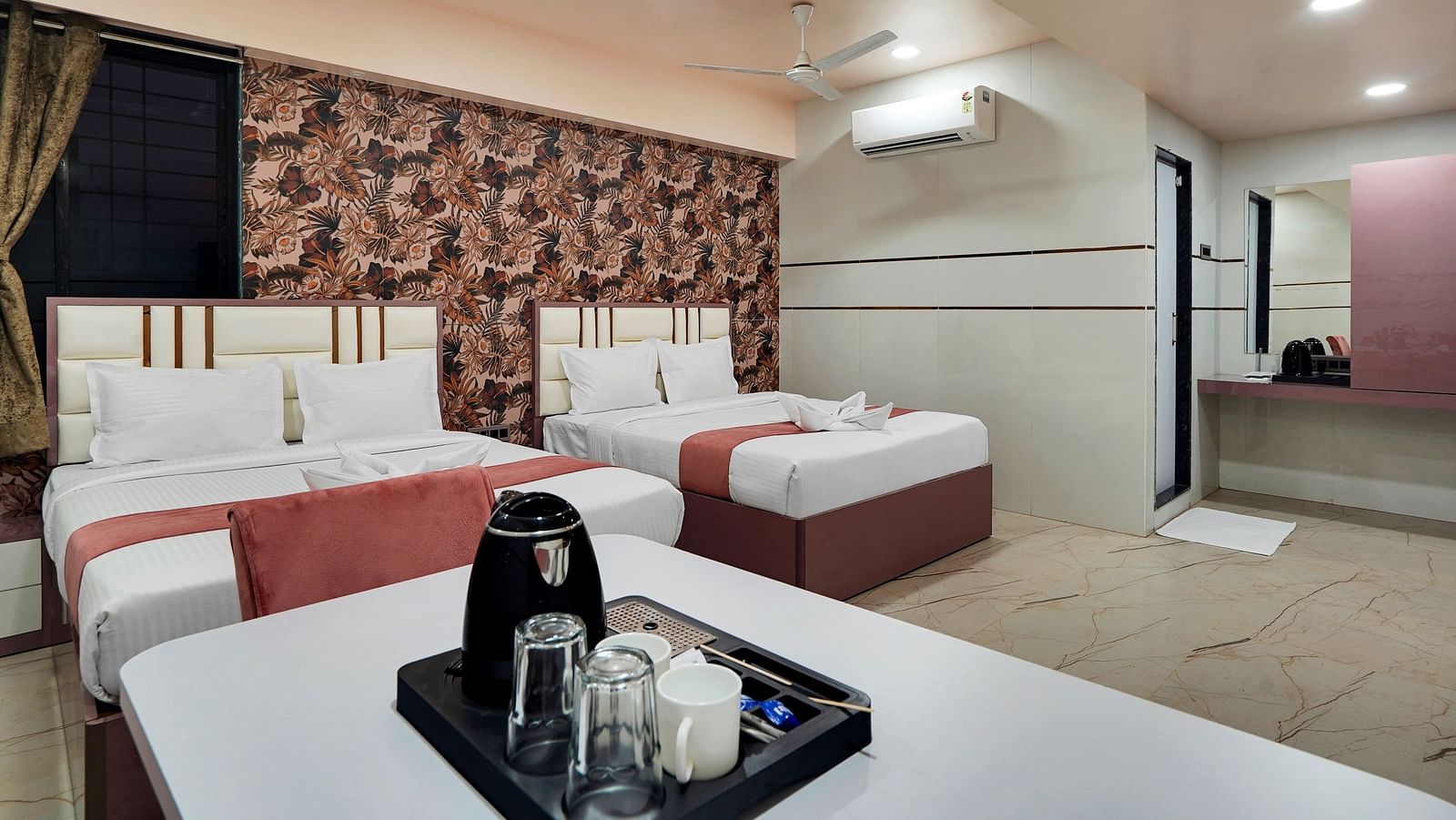 Two king size beds placed in front of table with tea & coffee maker in Family Room at Hotel Regal Heaven, Pune.
