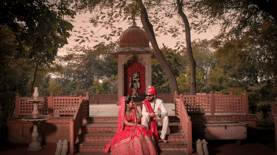 Bride and groom seated in a heritage courtyard during a traditional wedding photoshoot.