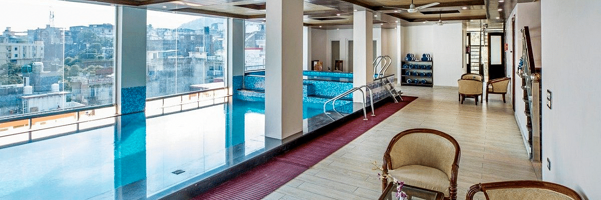 The lobby besides the swimming pool with a common seating area overlooking the city views from the glass window at Regenta Inn DLS.