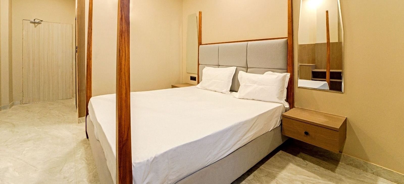 A bedroom at Grassfield Riveria Resort, Jaipur, with a four-poster bed, minimalist decor, and a private bathroom.
