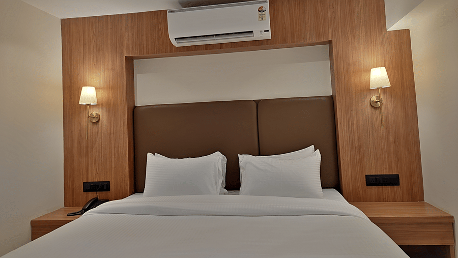 Bedroom with a double bed, wooden headboard, bedside lights, and air conditioner