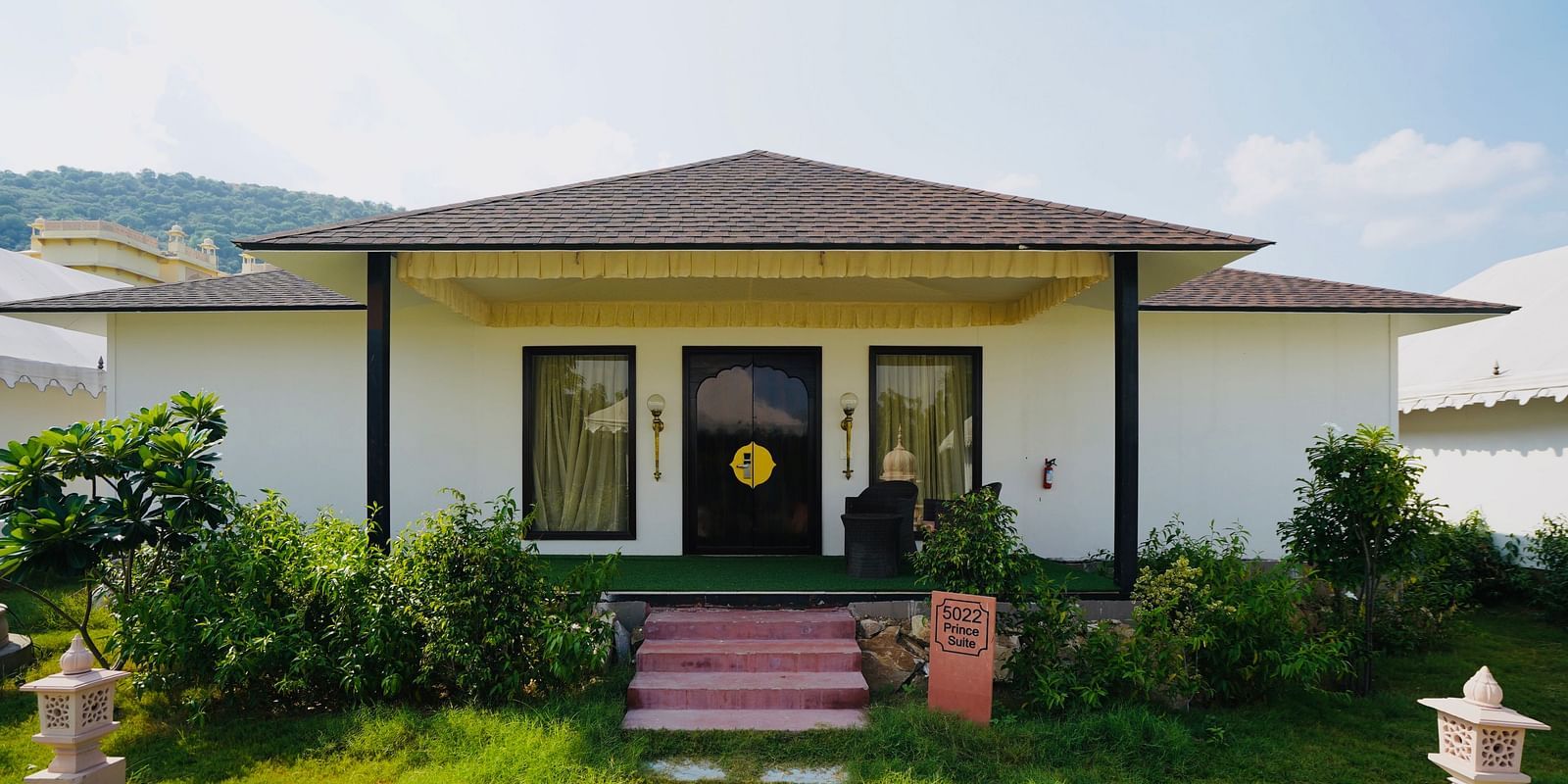 Facade of an accommodation with plants and grass surrounding it at Rajasthali Resort & Spa Jaipur.