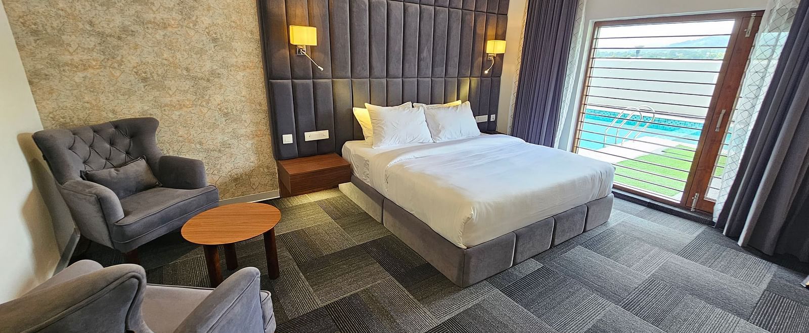 full view image of the premium room at Eminence The Corbett withe a comfortable double bed and huge windows besides it