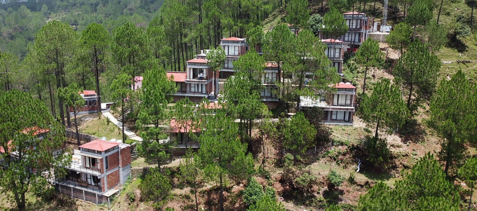 aerial view of the BluSalzz Escapade Resort, Lansdowne surrounded by green trees.