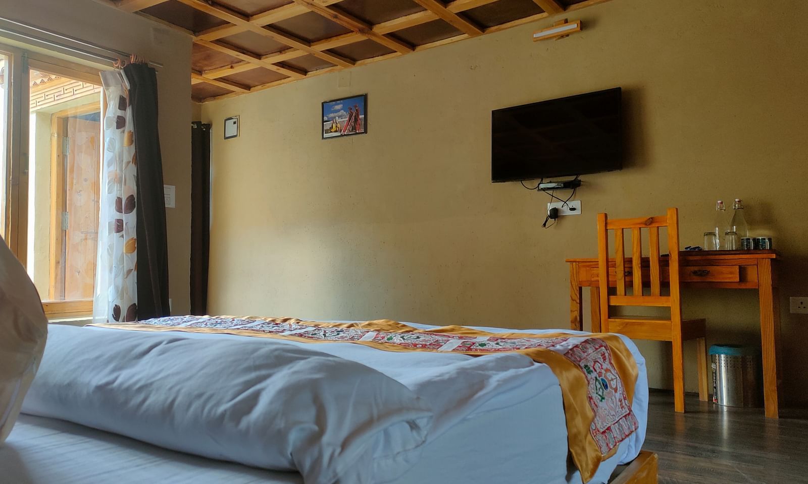 Standard Cottage with a king size bed, a wooden ceiling, and a TV on the wall at White Sands Resort, Ladakh.