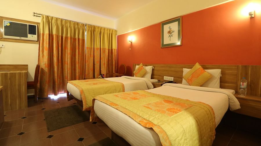 twin single beds with runners on it inside the Deluxe room at VITS Kamats Resort, Silvassa