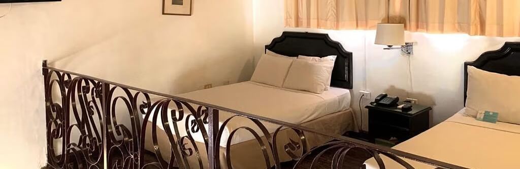 A bedroom with a bed and a decorative railing overlooking another area | Junior Suite | Altamont Court, Jamaica