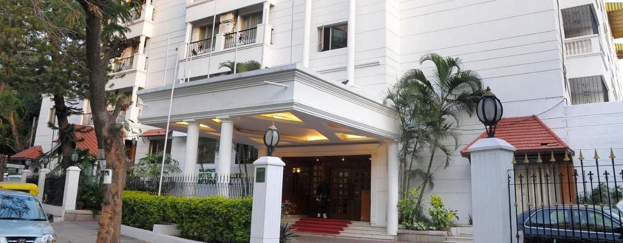 Nalapad Hotel Bangalore International, a white building with a covered entrance, landscaping, and parking.