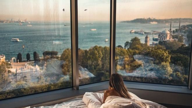 a woman lying down in a bed looking at the view outside from the window