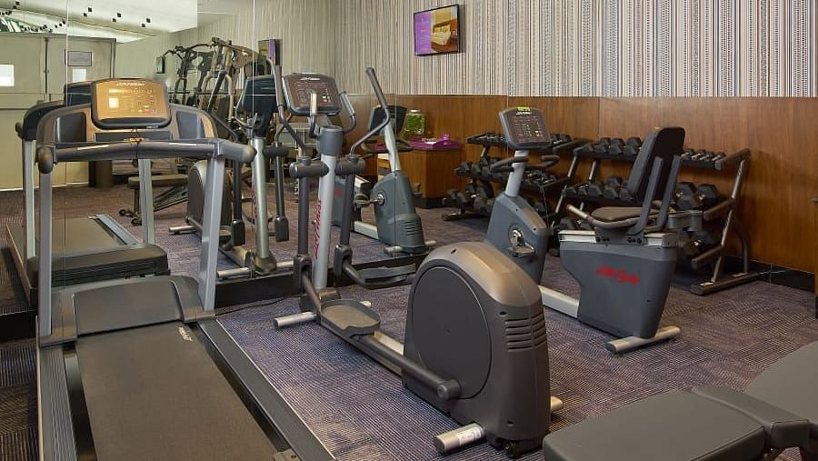 A spacious gym with various exercise equipment, including cardio and weightlifting machines, arranged neatly along the walls.