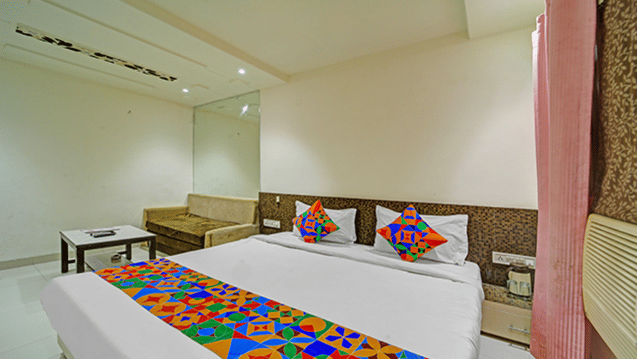 Twin beds with side table, wall panel design and open floor space at Hotel Maurya, Bhopal.
