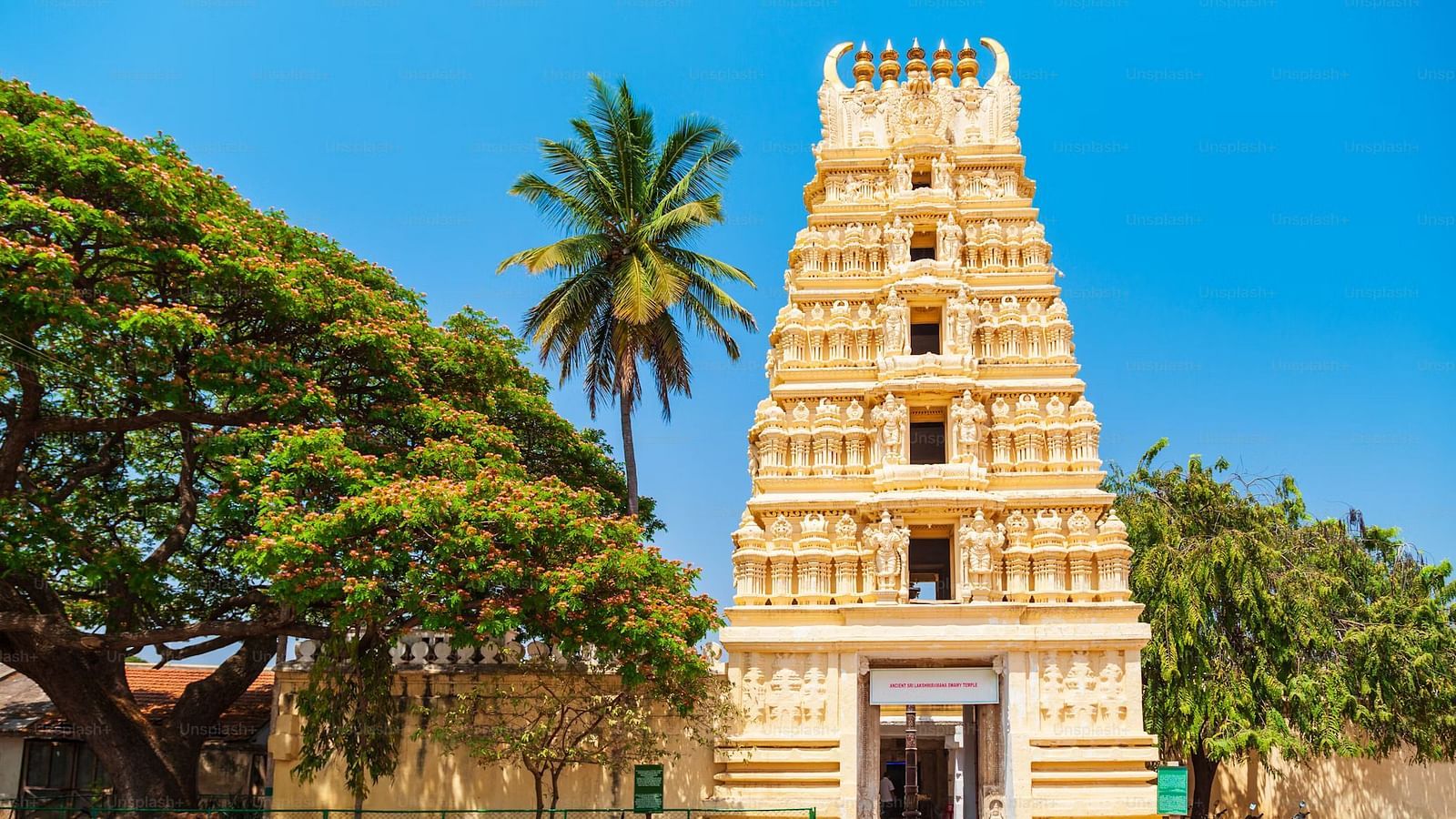 Temple with a towering gopuram, surrounded by palm trees and clear skies.