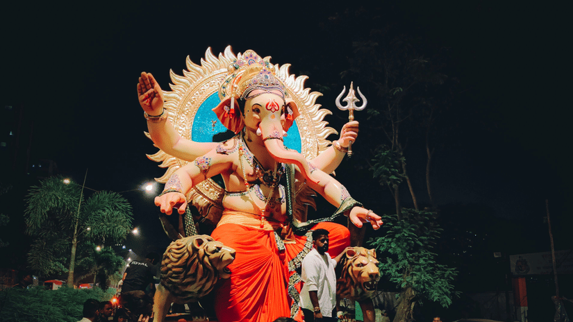 A view from below of a procession for the visarjan of Ganpati in Mumbai, with people surrounding the idol.