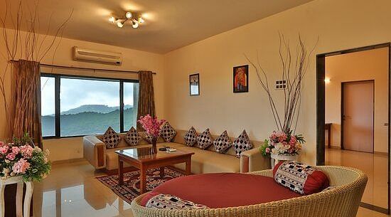 Image of living room of  a Pent House with a large window and spacious sofas - Camel Valley Resort, Igatpuri