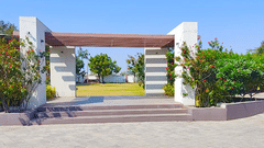 An arch at the entrance of Amber Lawn with greenery next to it - VITS Select, Rajkot.