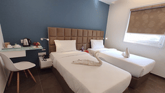 Twin beds with a study table and side tables inside Deluxe Twin Room - VITS Select, Rajkot.