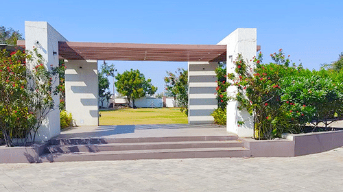 An arch at the entrance of Amber Lawn with greenery next to it - VITS Select, Rajkot.