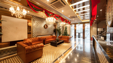 A lobby at Hotel Mamallaa Heritage, Mahabalipuram, with 4 sofas, a coffee table, a reception desk, and wall decorations.
