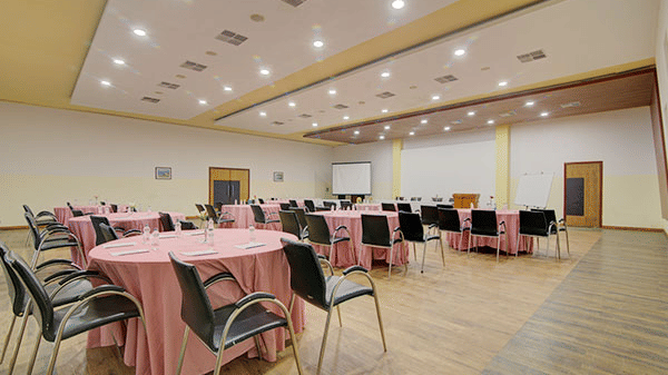 a banquet hall in a cluster style seating with chairs facing the projector screen - Camel Valley Resort, Igatpuri